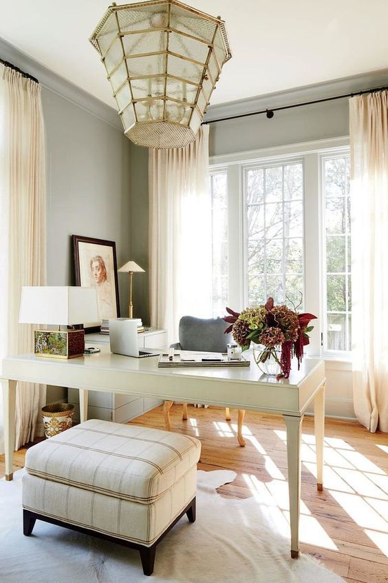 a white desk sitting in front of a window next to a chair and ottoman on top of a hard wood floor