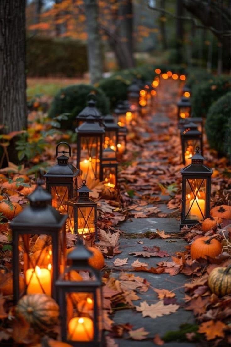 many lanterns are lit in the middle of a path with pumpkins and leaves on it