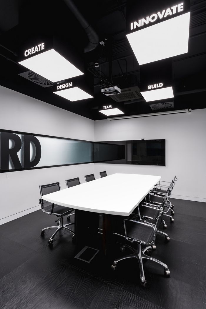 an empty conference room with black chairs and white table in front of large sign that says innovation