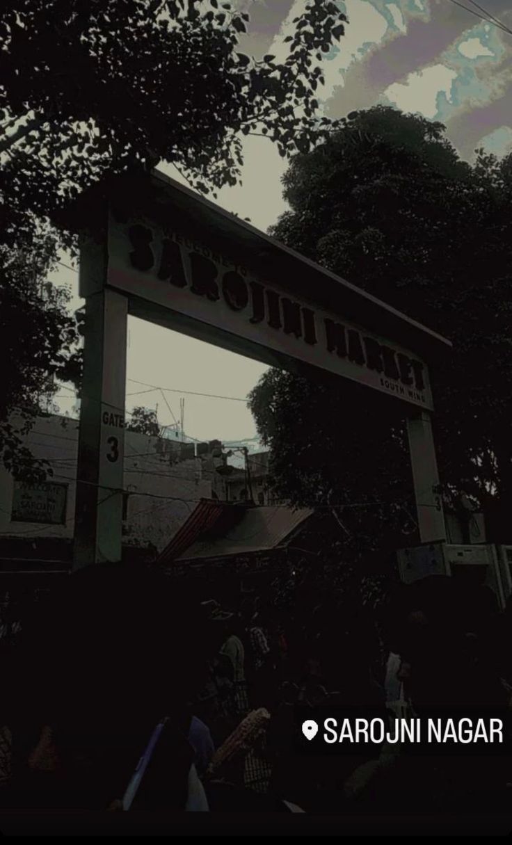 an image of a sign that is in the air with people around it and trees behind it