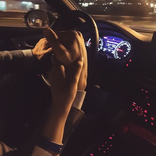 a person driving a car at night with their hands on the steering wheel