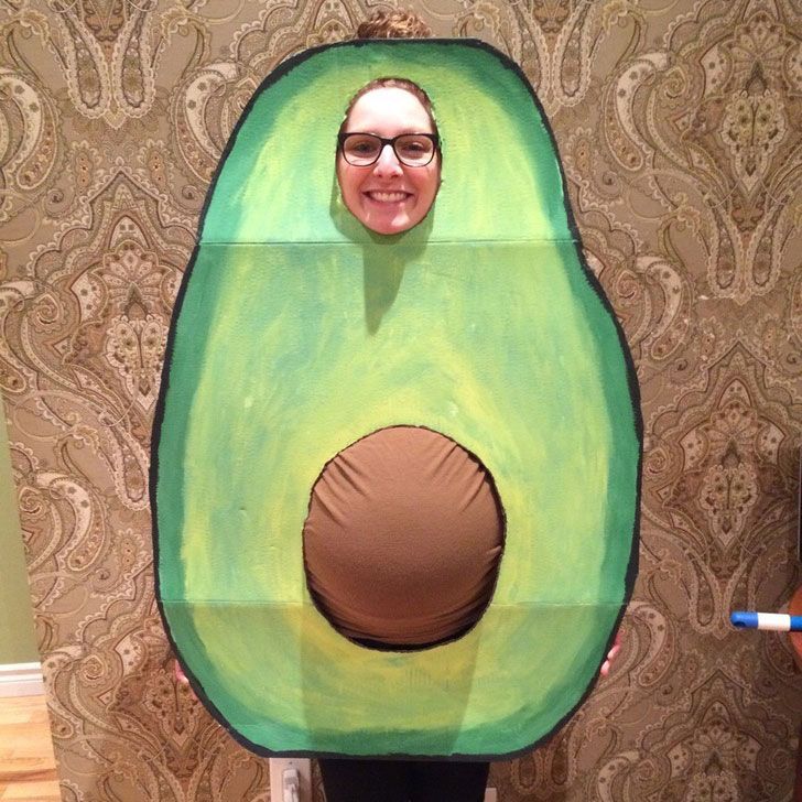 a person standing in front of a wall with an avocado costume on it