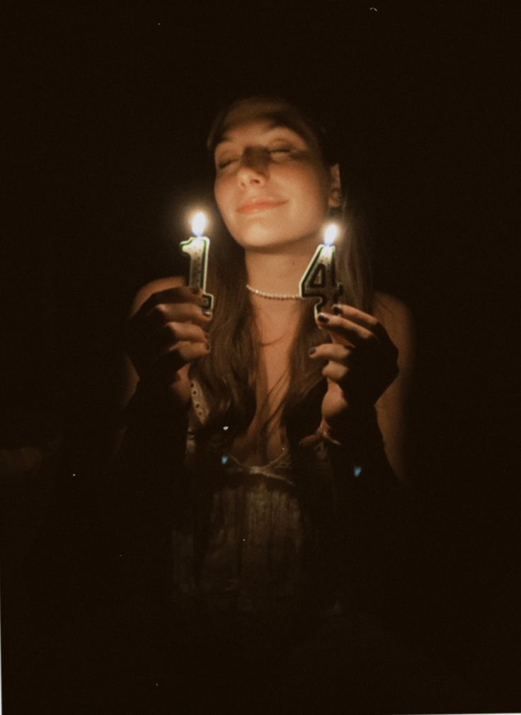 a woman holding two candles in her hands