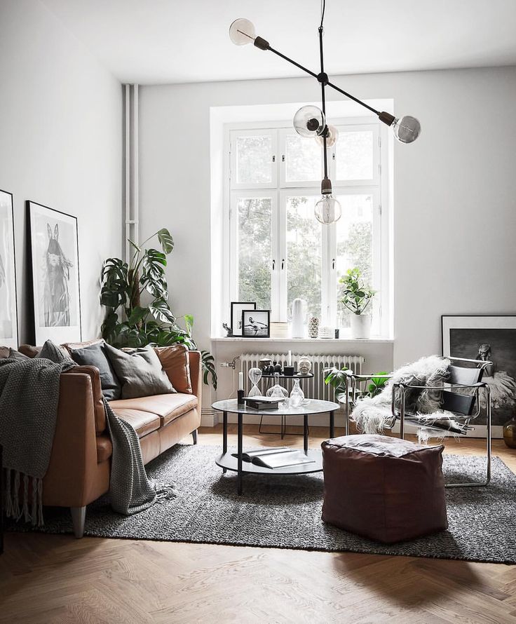 a living room with white walls and wooden floors, two couches in front of a large window