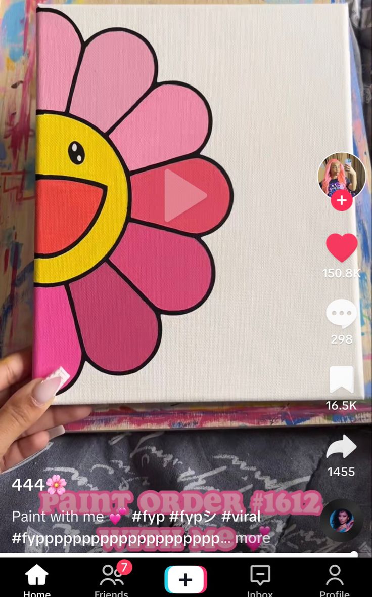 someone is holding up a painting with a flower on it