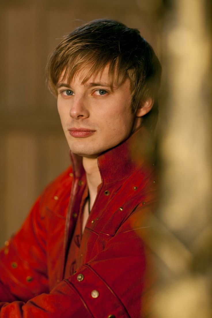 a young man in a red jacket looking at the camera