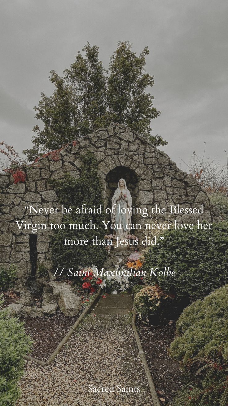 a stone building with a statue in the middle and a quote on it that says never be afraid of loving the blessed virgin too