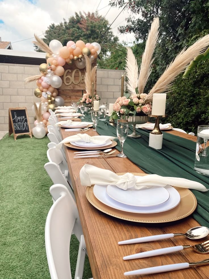 a long table set up with plates and silverware for an outdoor dinner or party