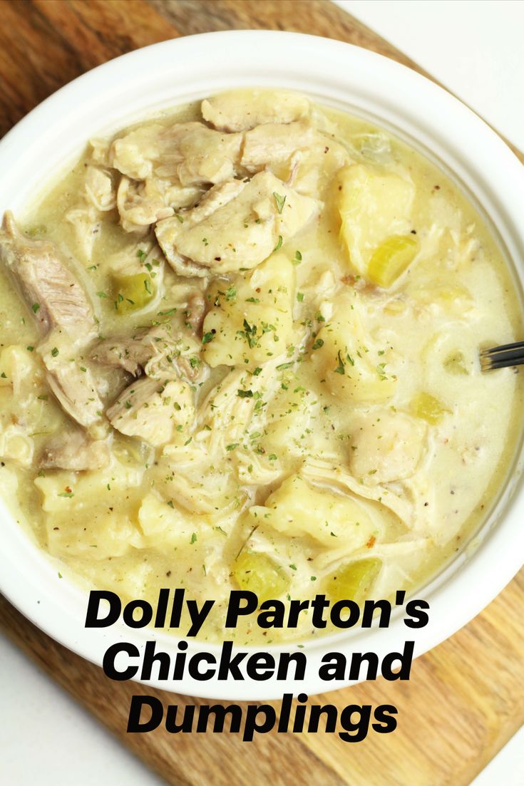 a white bowl filled with chicken and dumplings on top of a wooden cutting board