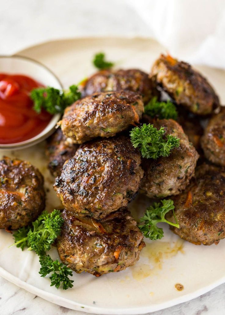 some meatballs on a plate with ketchup and parsley next to it