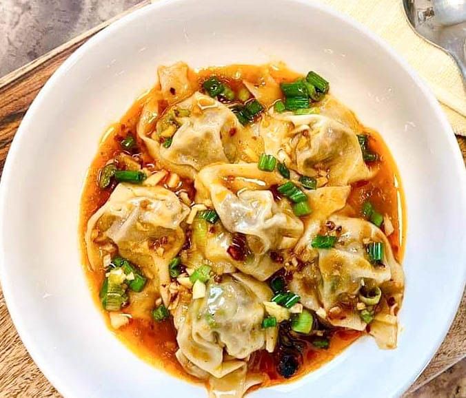 a white plate topped with dumplings covered in sauce