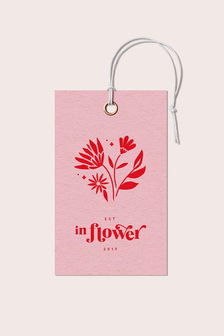 a pink gift tag with the words in flower printed on it and a white string