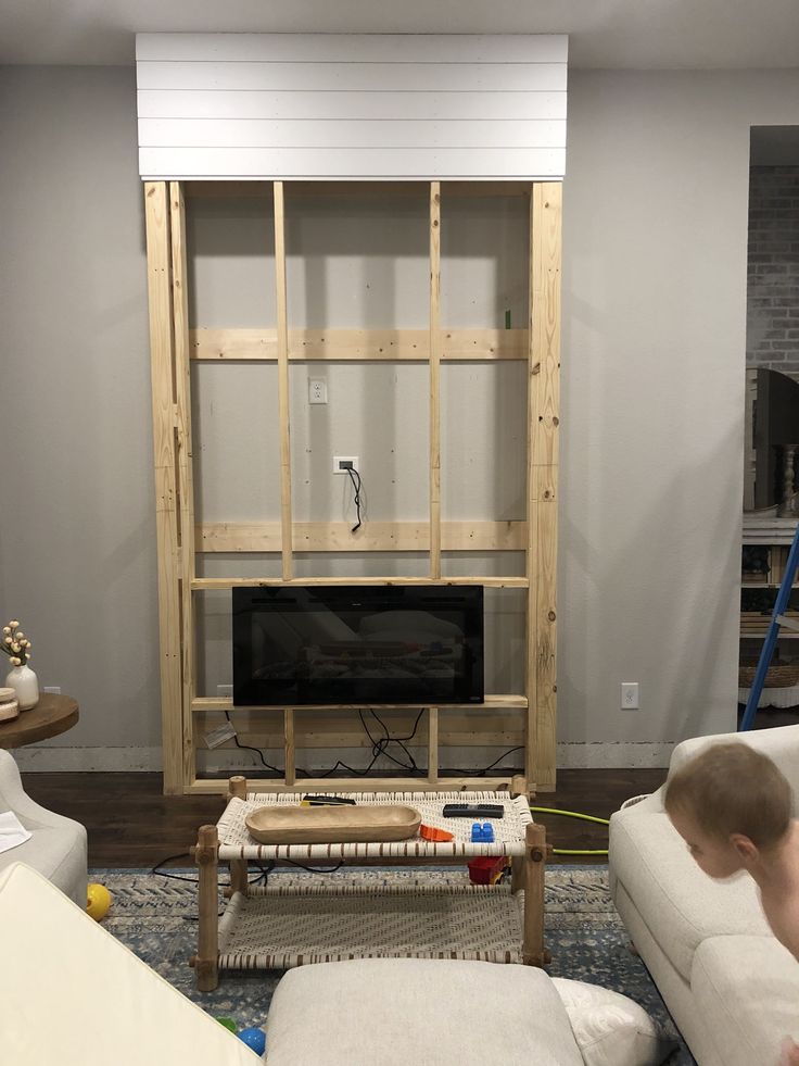 a living room filled with furniture and a flat screen tv on top of a wooden shelf