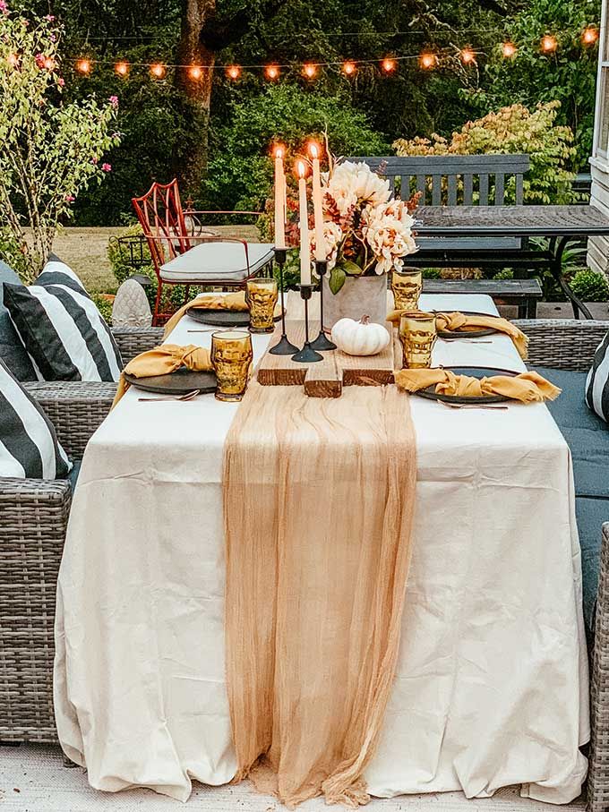 an outdoor dining table set with candles and flowers