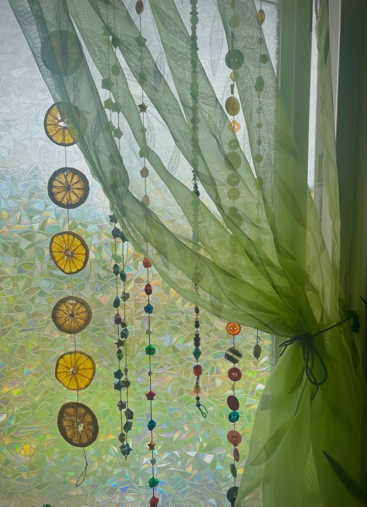 a window with some beads hanging from it's side and a curtain in the background