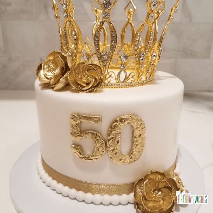 a white cake with gold decorations and a crown on top