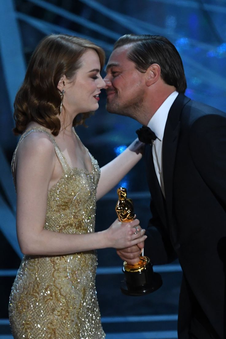 the actors kissing each other in front of an oscars stage with one holding his award