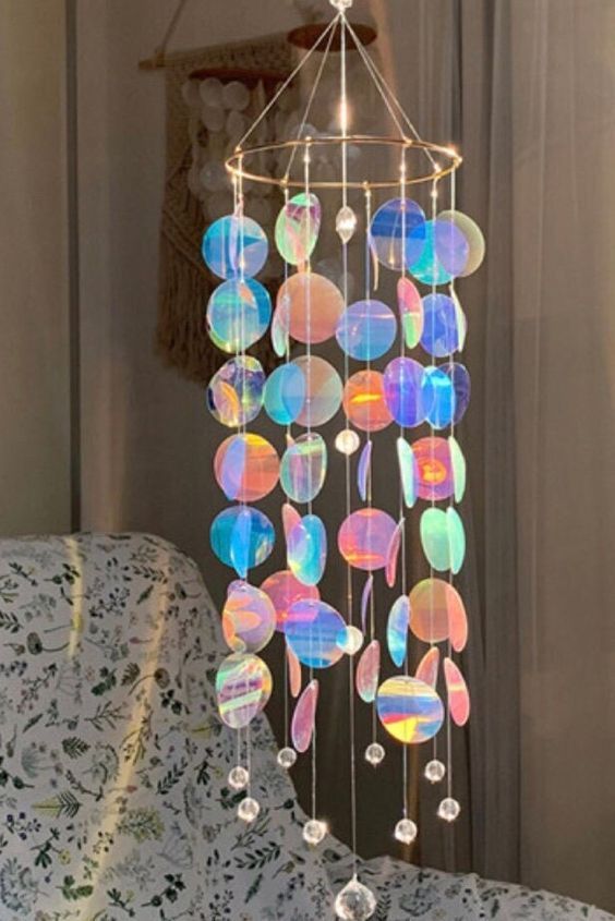 a wind chime hanging from the ceiling in front of a window with white curtains