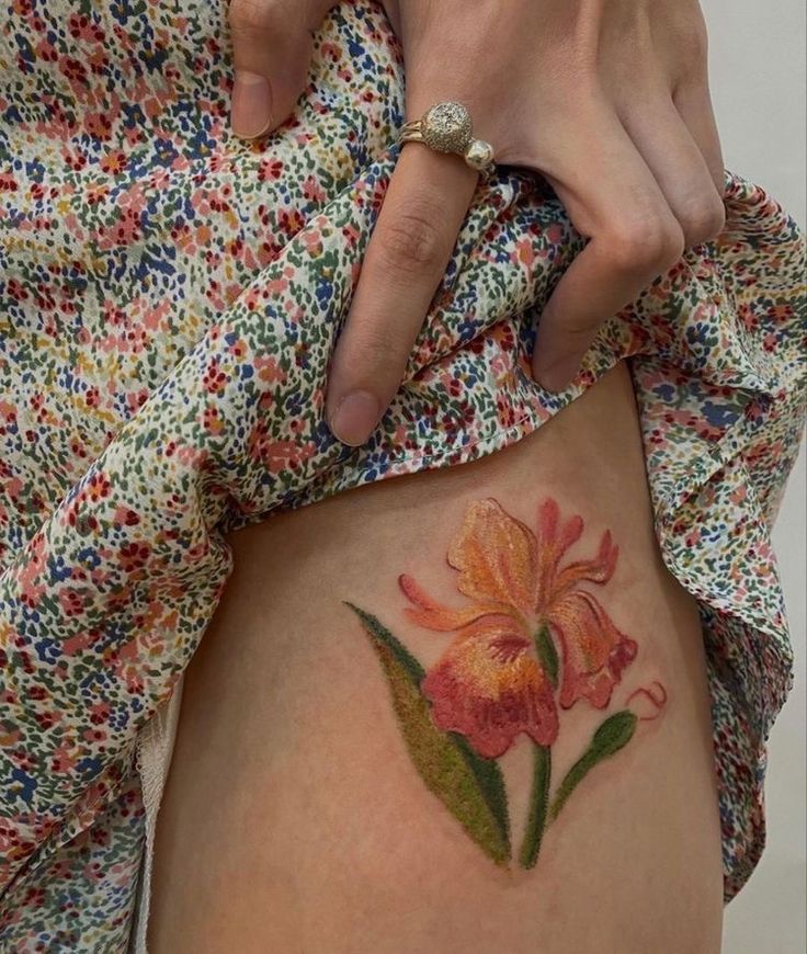 a woman with a flower tattoo on her stomach is holding onto the side of her thigh