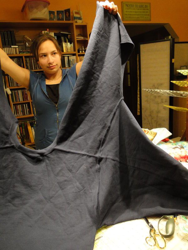 a woman holding up a black cloth in front of a bookshelf