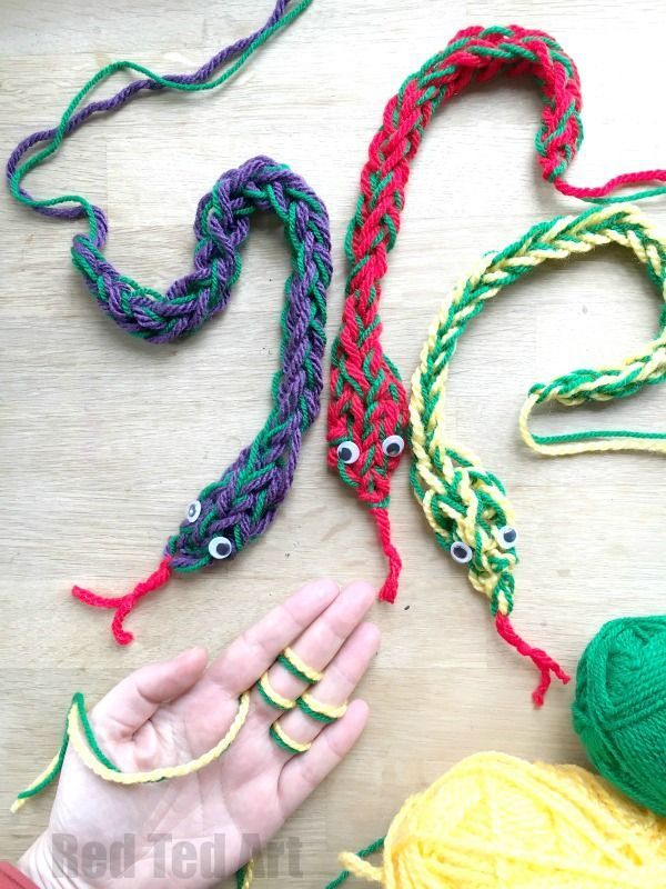 someone is holding their hand near some yarns and crochet hooks on the table