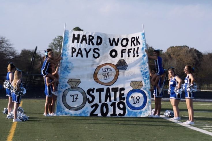 some cheerleaders are standing in front of a sign that says hard work pays off