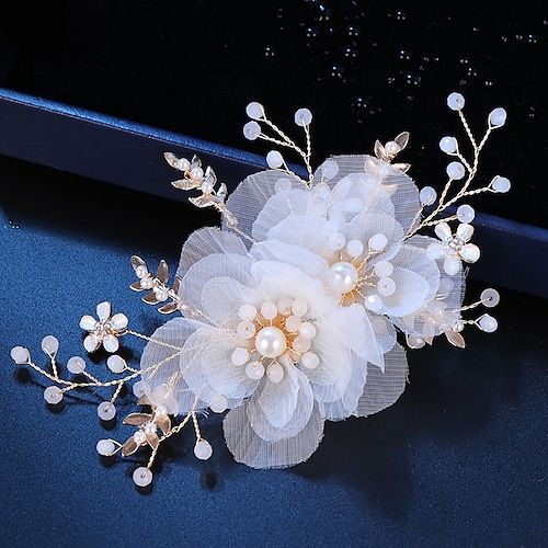 a white flower and pearl hair comb on a dark blue surface with water droplets in the background