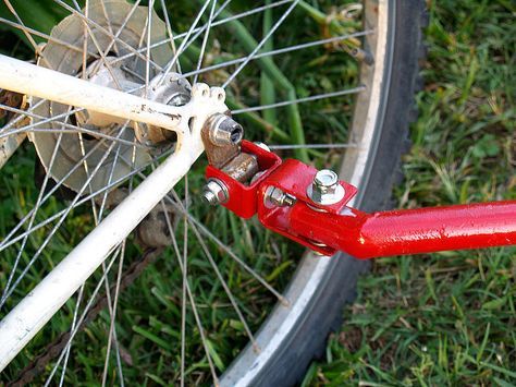 a close up of a bicycle tire and red handlebars with grass in the background