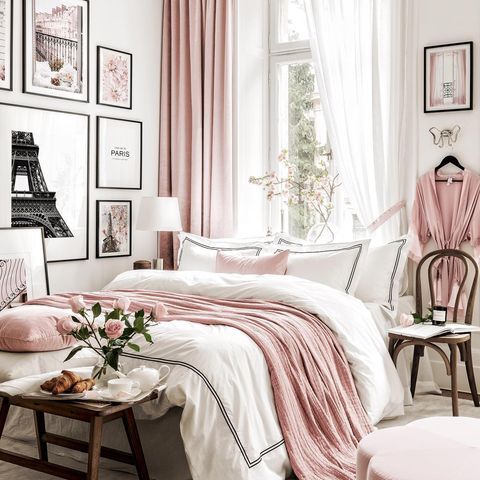 a bedroom decorated in pink and white with pictures on the wall