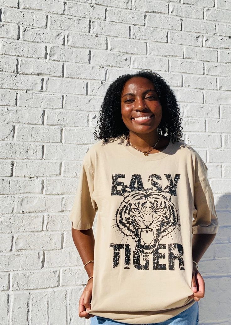 Stay on-trend with the Easy Tiger Oversized Graphic Tee. This tan-colored shirt is designed with a slightly oversized fit, providing both comfort and style. Perfect for any casual occasion, this tee is a must-have for any fashion-forward individual. Oversized Brown T-shirt For Fall, Trendy Khaki Crew Neck T-shirt, Trendy Brown Relaxed Fit T-shirt, Trendy Oversized T-shirt For Everyday, Trendy Beige Relaxed Fit T-shirt, Trendy Beige T-shirt For Streetwear, Oversized Brown T-shirt, Trendy Beige Streetwear T-shirt, Casual Beige T-shirt With Letter Print