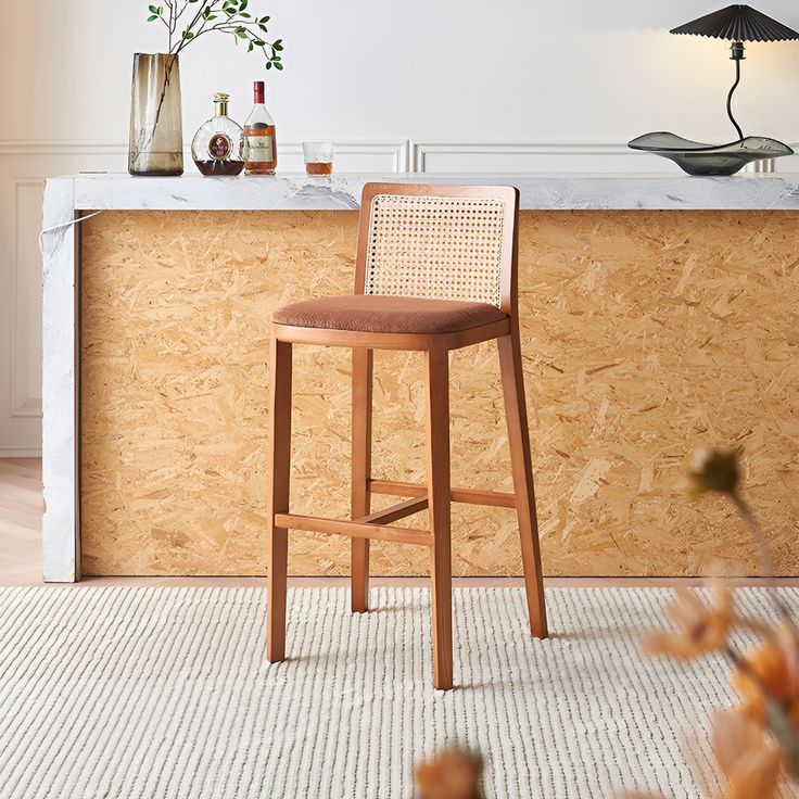 a wooden bar stool sitting in front of a counter with bottles and vases on it