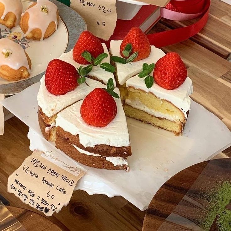 there is a cake with white frosting and strawberries on the top, along with other pastries