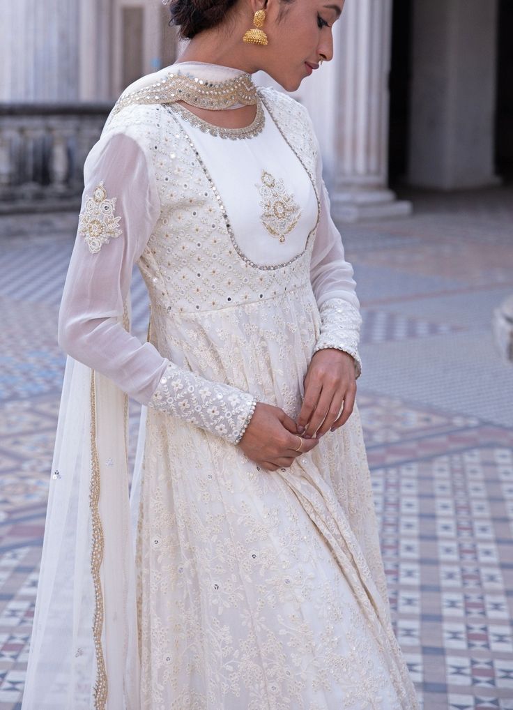 This look features an ivory anarkali set. The closed neck, full sleeves set has a yoke with an embroidered motif and a flowy ghera. Inspired by the royal palaces, it is embellished with mirror, threadwork, pearls, zardozi and sequins all over. A matching net dupatta with scallop border and bootis completes the look. Composition: Anarkali - Viscose georgette, Dupatta - Soft net, Churidar - Lycra Care: Dry Clean Only and Vacuum Storage This product can be customised for colour, sleeves, length of blouse and neck design Delivery : 2 weeks as the product is hand crafted. For more information and sizes please contact fabiliciousfashion@gmail.com or visit our Copenhagen studio.About the Designer : Renee Label was created in 2013,by the talented sister duo Pooja and Karuna, is a culmination of th Traditional Anarkali Set With Mirror Work And Long Sleeves, Designer Semi-stitched Off White Churidar, Semi-stitched Cream Anarkali Salwar Kameez, Cream Floor-length Anarkali Kurta, Cream Floor-length Salwar Kameez For Diwali, Semi-stitched Anarkali Salwar Kameez In Cream, Semi-stitched Cream Anarkali Sharara, Anarkali Salwar Kameez In Cream, Cream Anarkali Salwar Kameez Semi-stitched