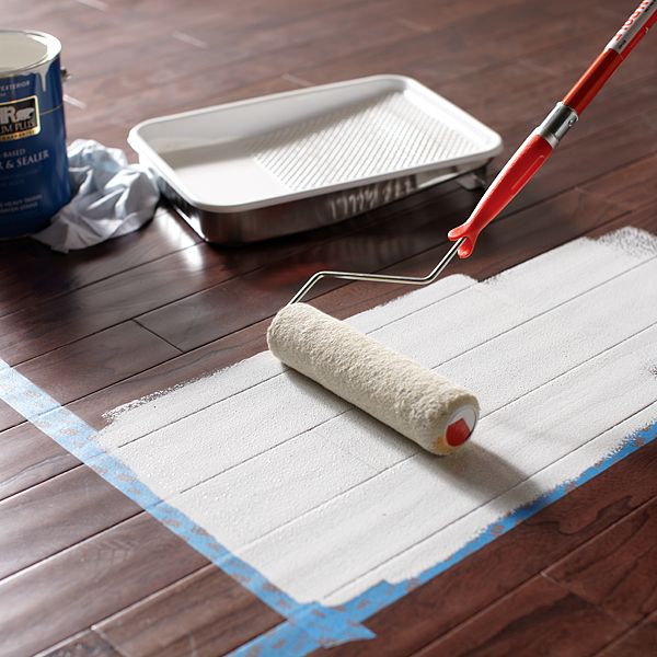 a roll of toilet paper is being painted on the floor by a paint roller and a spatula