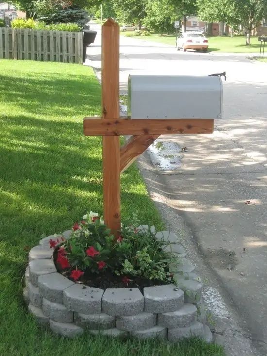 a wooden cross sitting on the side of a road next to a flower pot filled with flowers