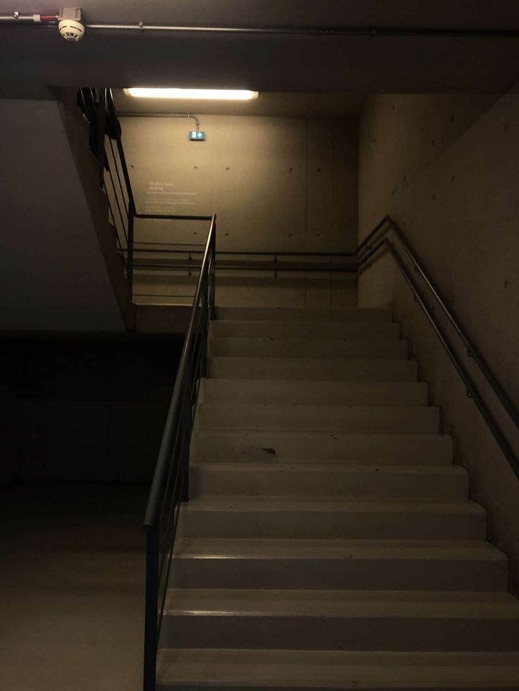 an empty stairwell with stairs leading up to the second floor and light on above it