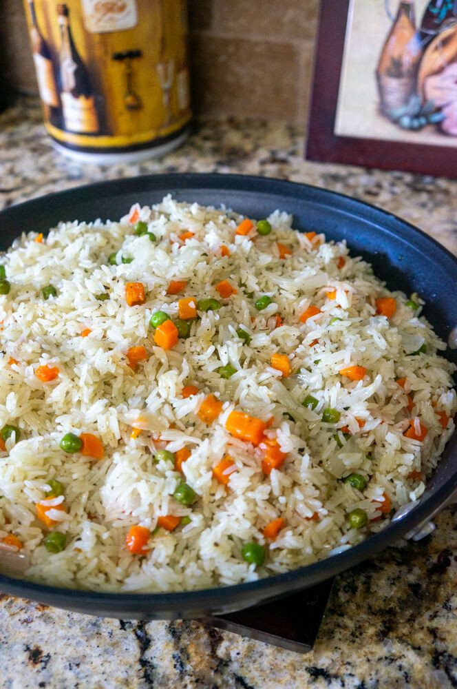 a pan filled with rice and carrots on top of a counter next to a can of beer