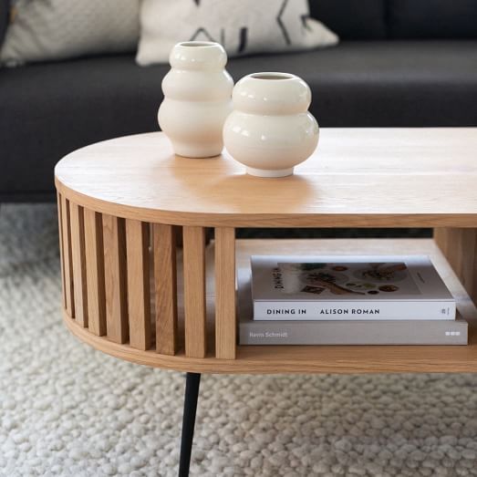 a coffee table with two white vases on top and a book in the middle