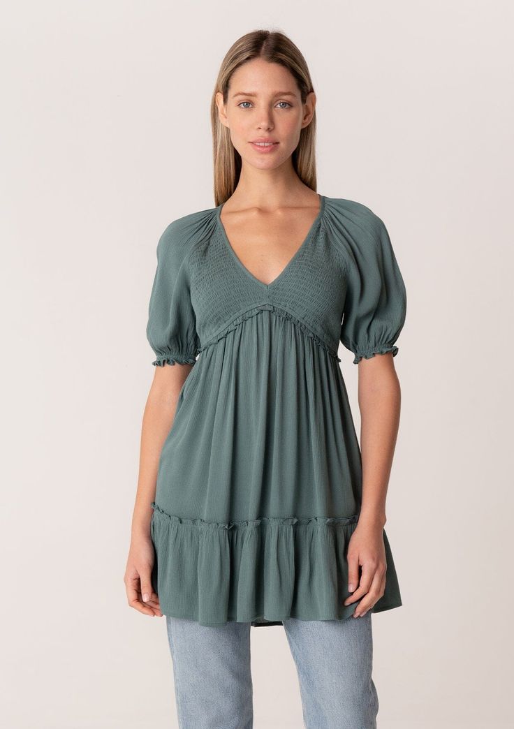 [Color: Lagoon] A front facing image of a blonde model wearing a bohemian spring tunic top in a teal crinkled fabric. With short puff sleeves Spring V-neck Smocked Top With Gathered Sleeves, Bohemian V-neck Top With Smocked Back, Bohemian V-neck Tops With Smocked Back, Flowy Puff Sleeve Tops With Elastic Sleeves, Casual V-neck Peasant Top With Smocked Bodice, Bohemian Smocked Puff Sleeve Dress, Bohemian Smocked Flowy Dress With Ruched Detail, Chic Smocked Dress With Short Elastic Sleeves, Bohemian Smocked Ruched Flowy Dress