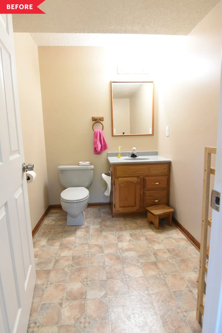 a bathroom with a toilet, sink and mirror next to a wooden cabinet in the corner