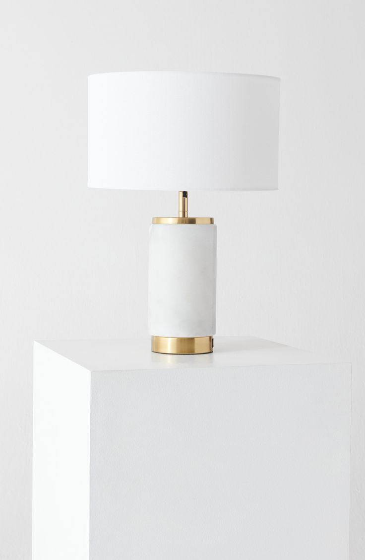 a white table lamp with a gold base