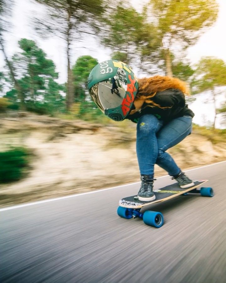 a person riding a skateboard down a road with trees in the backgroud