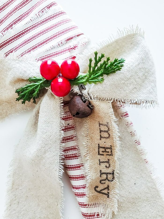 a burlap christmas bow with holly and red berries hanging from it's side