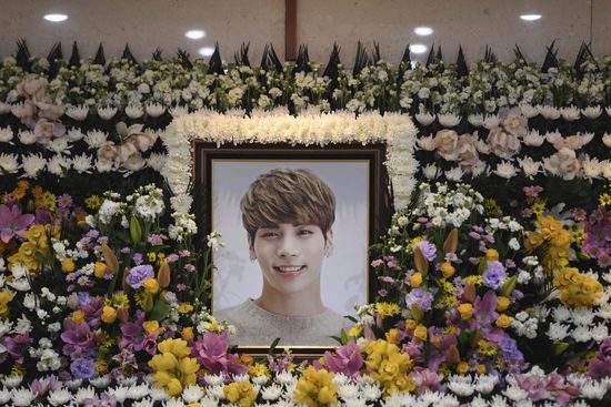 a cross and flowers are in front of a photo of a young man on the wall