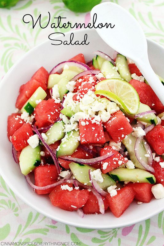 watermelon, cucumber and onion salad in a white bowl with spoons