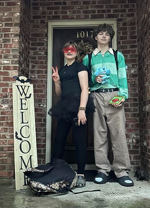 two people standing in front of a brick building with a welcome sign next to them