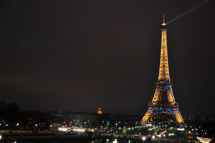 the eiffel tower lit up at night with lights on it's sides