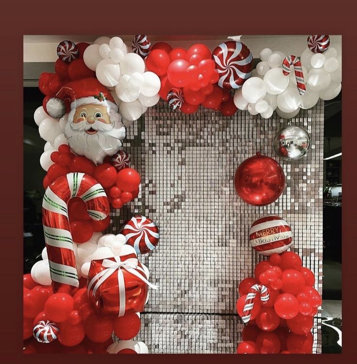 a christmas wreath made out of red and white balloons, candy canes, and santa's head