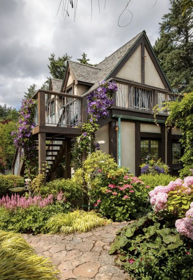 the house is surrounded by beautiful flowers and greenery