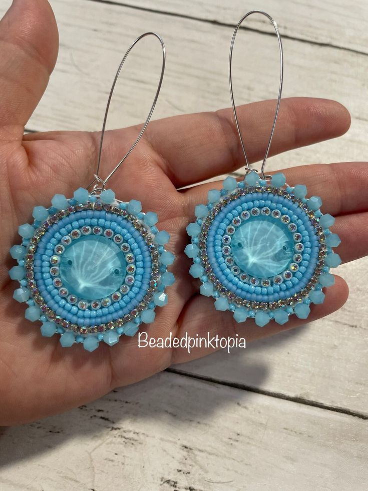 a pair of blue beaded earrings on a person's hand